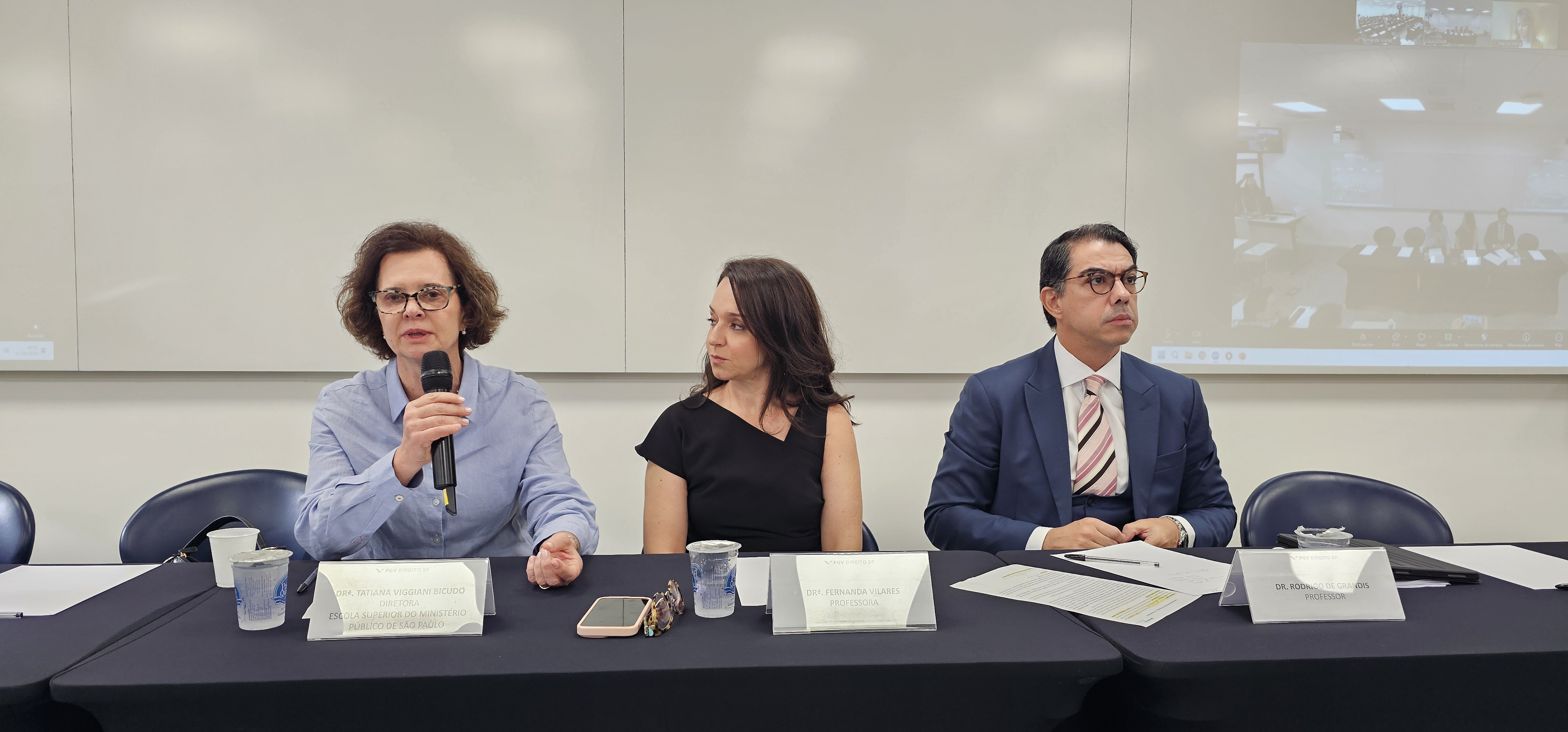 foto mostra diretora da ESMPSP na mesa de abertura do evento. Fim da descrição. 