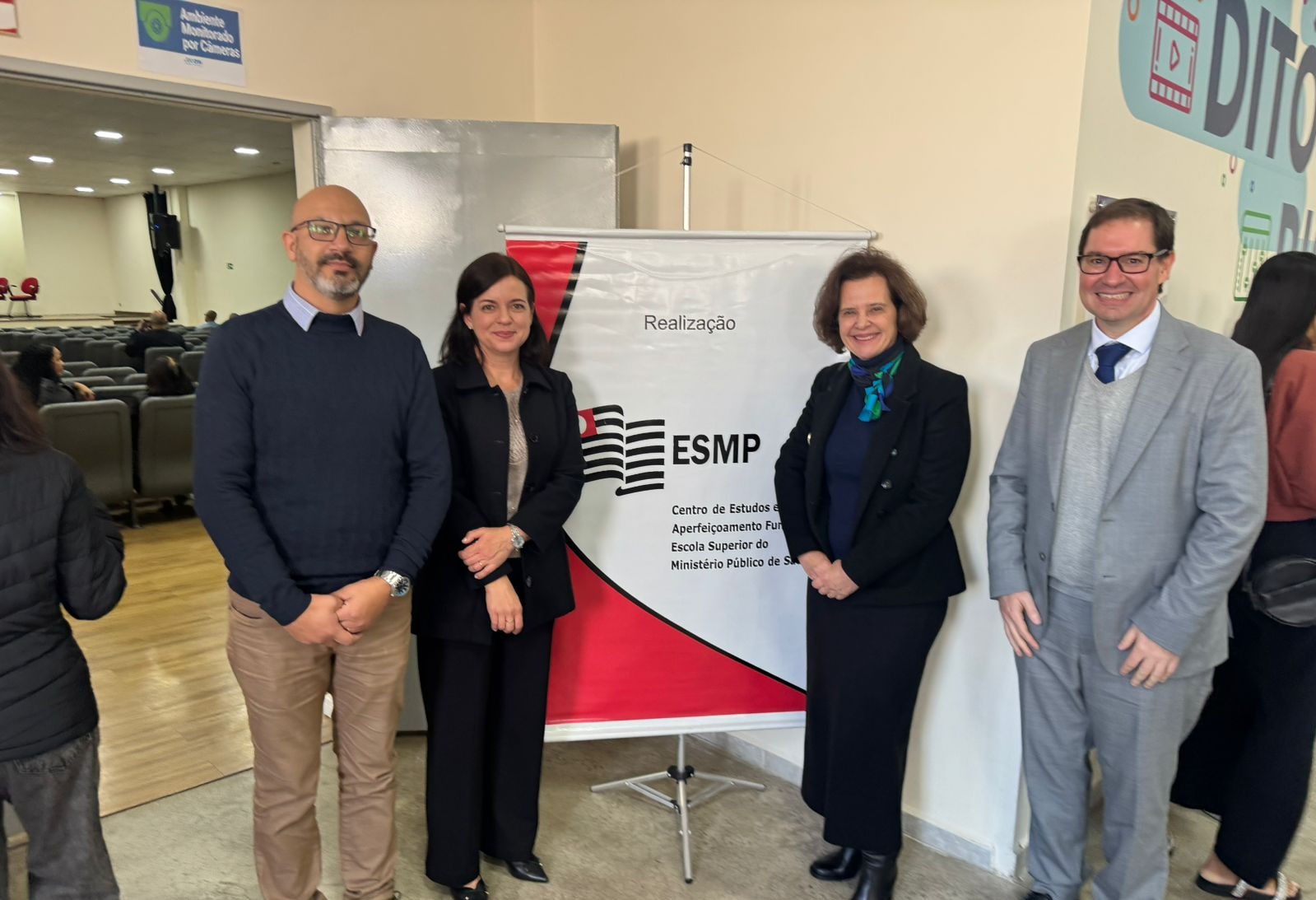 Foto mostra diretora da ESMPSP e demais participantes do evento. Fim da descrição.