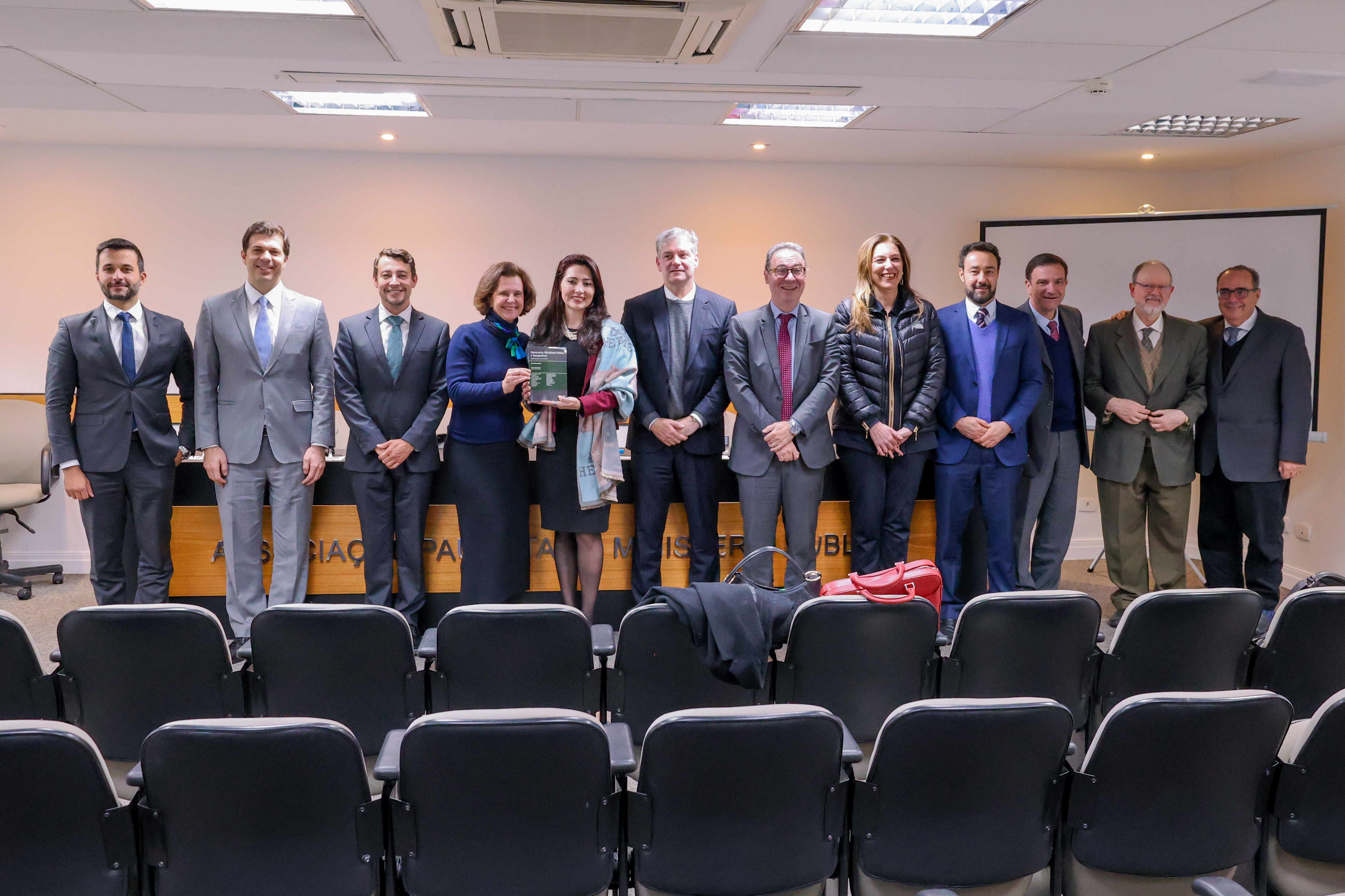 Foto mostra a diretora da ESMPSP e demais participantes do evento. Fim da descrição. 